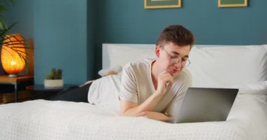 Genç bir öğrenci bilgisayar ekranına bakarak ve eğlenceli sosyal medya videoları izleyerek ya da internet üzerinden yayın yaparak evde teknoloji cihazıyla eğlenerek eğleniyor..