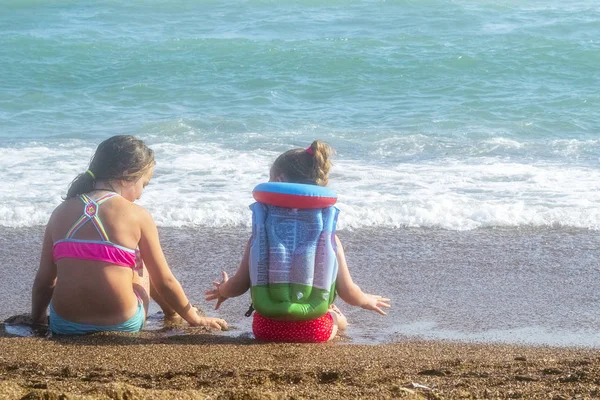 Niñas sentadas en la playa y mirando al mar — Foto de Stock