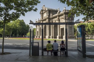 Madrid, İspanya - 4 Ağustos 2018: Alcala kapısı veya Puerta de Alcala, otobüs durağında bekleyen üç yolcuları bir Plaza de la Independencia Madrid, İspanya içinde abidesi