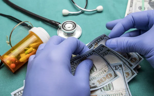 病院で 100 ドル札を数えるブルー ラテックス手袋と医師 — ストック写真