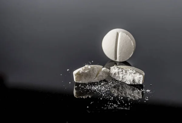White pill by half isolated in black background, conceptual image