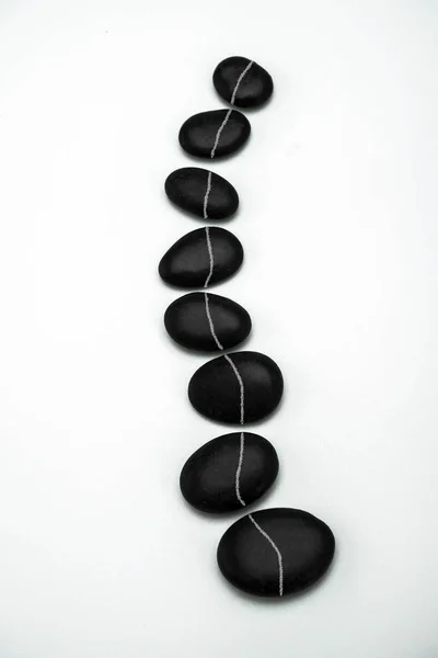 Formation of black stones imitating the vertebral column, isolated in white background, conceptual image