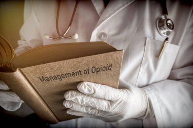 Doctor holds book on Management of Opioid, conceptual image clipart
