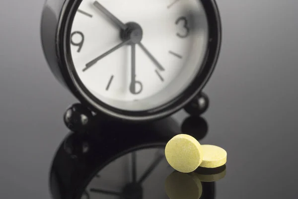 Gele Pillen Naast Een Klok Conceptueel Beeld — Stockfoto