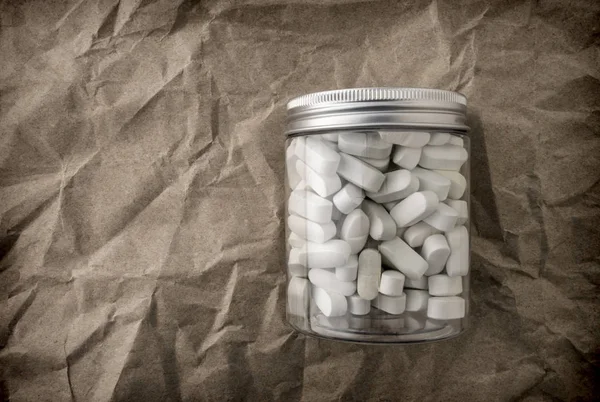 しわくちゃの紙の背景 概念図に白い錠剤のボトル — ストック写真