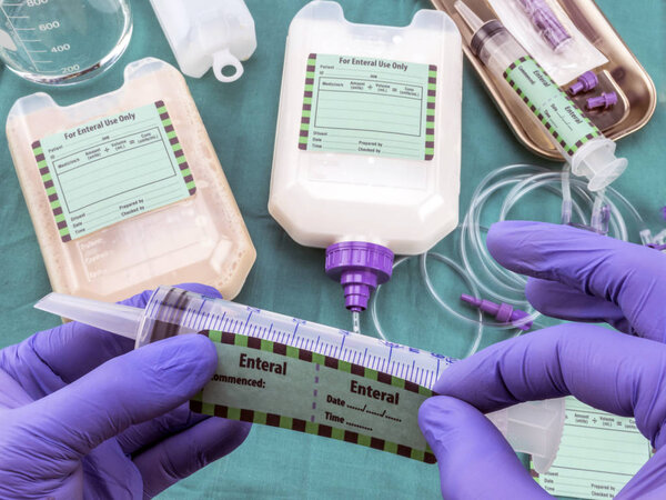 Медсестра нанесла этикетку на шприц энтерального питания, паллиативную помощь в стационаре, концептуальный образ, композицию хотизонтальной
