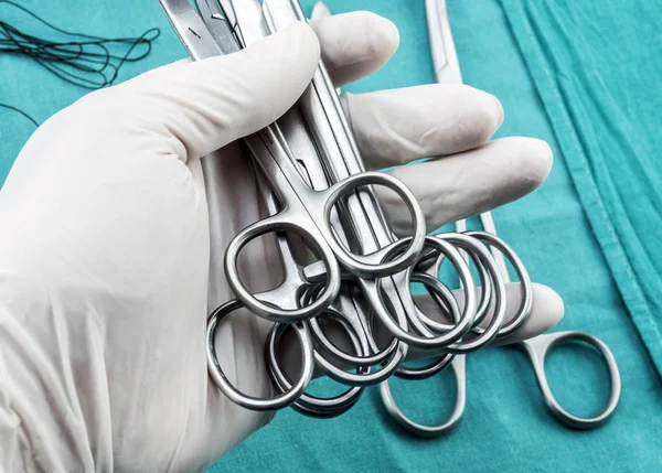 Cirujano trabajando en quirófano, manos con guantes sosteniendo suturas de tijeras, imagen conceptual, composicon horizontal — Foto de Stock
