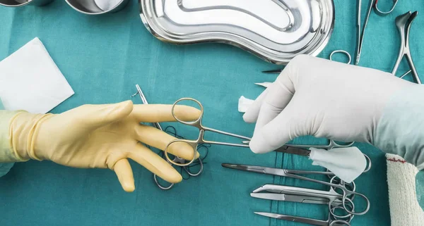 Chirurg im Operationssaal, Hände mit Handschuhen, die eine Schere aus Naht und Torundas halten, konzeptionelles Bild, horizontales Composicon — Stockfoto