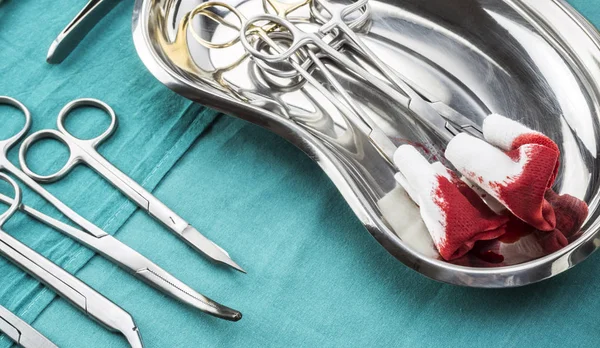 Tijeras quirúrgicas con torundas empapadas de sangre en una bandeja metálica en un quirófano, composición horizontal, imagen conceptual — Foto de Stock