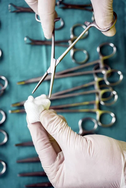 Chirurg im Operationssaal, Hände mit Handschuhen, die eine Schere mit Torunda halten, konzeptionelles Bild, vertikale Komposition — Stockfoto