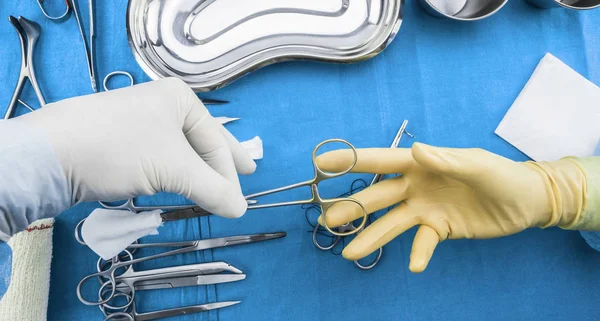 Cirujano trabajando en quirófano, manos con guantes sosteniendo tijeras de sutura y torundas, imagen conceptual, composicon horizontal — Foto de Stock