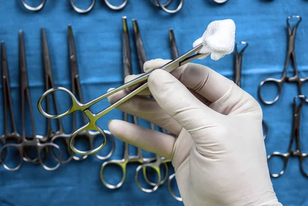 Kirurg som arbetar i Operations salen, händer med handskar som håller sax med torunda, konceptuell bild, horisontell komposition — Stockfoto