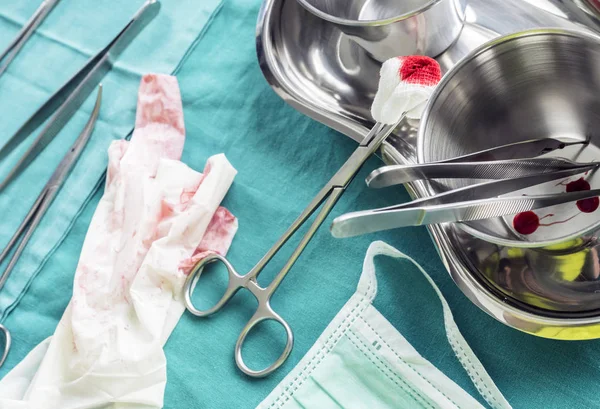 Tijeras quirúrgicas con torunda empapada de sangre en una bandeja metálica en un quirófano, composición horizontal, imagen conceptual — Foto de Stock