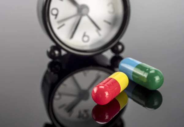 Pilulky vedle hodin, koncepční obrázek — Stock fotografie