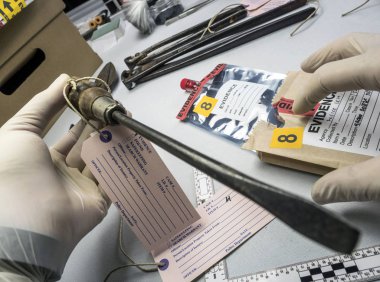 Uzman polis laboratuvar adli ekipman, kavramsal görüntü büyüteç bir tornavida ile inceliyor