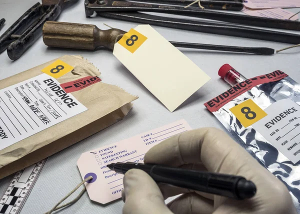 Especialista em polícia escreve sobre número de evidência de etiqueta, Vários testes de laboratório equipamentos forenses, imagem conceitual — Fotografia de Stock