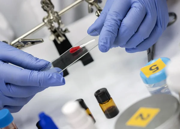 Cientista Polícia realizar suporte microscópio swab com vestígios de sangue, imagem conceitual — Fotografia de Stock