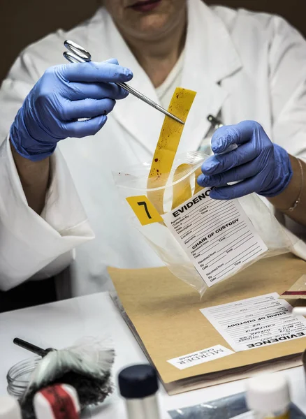 La police spécialisée analyse la gomme avec des traces de sang d'une victime surdose avec une pince à épiler, image conceptuelle — Photo