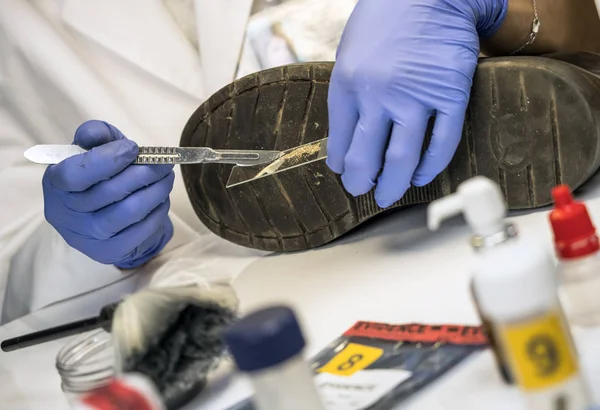 Spezialpolizist analysiert Boden im Schuh eines Opfers mit einer Pinzette, konzeptionelles Bild — Stockfoto