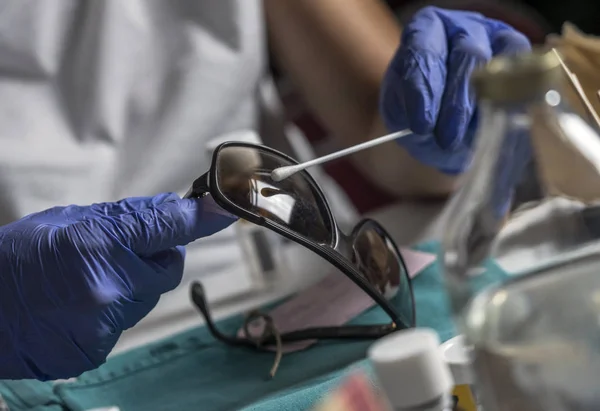 Especialista policial examina pin de vidrios manchados con sangre perteneciente a la víctima del asesinato, imagen conceptual — Foto de Stock