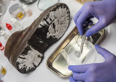 Uzman polis memuru, kurbanın ayakkabı cinayetinin zeminini tek bir cımbızla analiz ediyor.