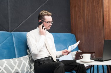 işadamı / bir adam kahve ve dizüstü bilgisayar ile kahve masasının otel lobisinde oturuyor.