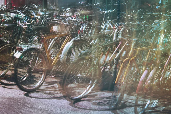 Many parked bicycles. Background image of congestion of bikes in a city (intentionally chaotic picture due to a reflection on a glass)