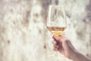 Paslı arka planda bir bardak şarap, kadın eli geleneksel İtalyan içeceğini tutuyor.