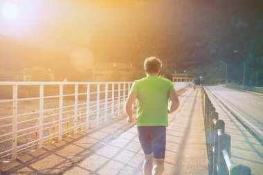 Yolun kenarında koşan adam. Bir sokakta koşucular ve bisikletçiler için spor eğitimi (rota engellerle korunmaktadır)