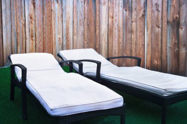 Güverte sandalyeleri spa, ahşap yastıklı hasır nesne ve çimen arka planı