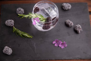 böğürtlen, biberiye bir sprig ve süs çiçeği ile cin ve tonik