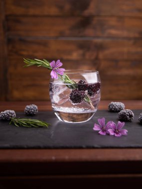 böğürtlen, biberiye bir sprig ve süs çiçeği ile cin ve tonik