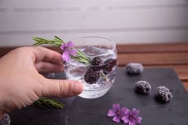 böğürtlen, biberiye bir sprig ve süs çiçeği ile cin ve tonik