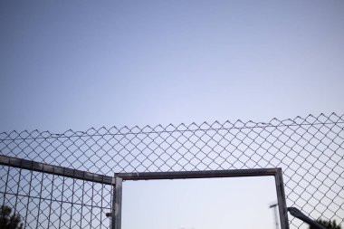Günbatımında odaklanmamış arka plan ile tel çit