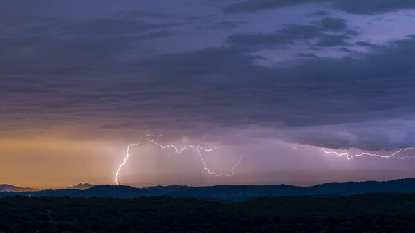 Захватывающий дух вид мощной грозы над холмами вечером
