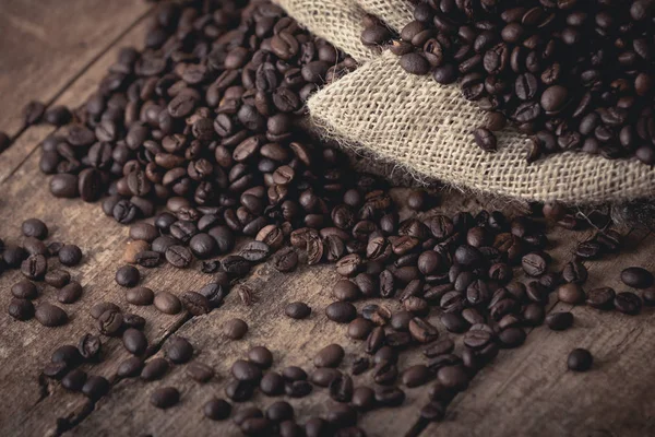 在褐色的背景上洒上新鲜咖啡豆的麻袋 — 图库照片