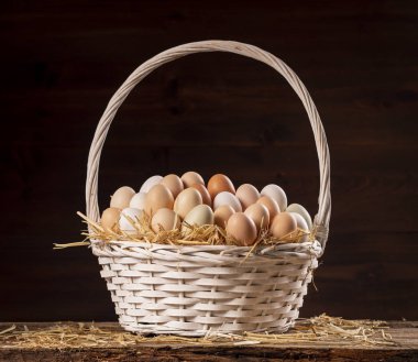 Koyu arka plan üzerinde taze çiğ yumurta ile hasır sepet