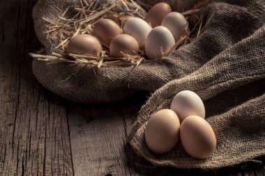 Ahşap masa üzerine keten kumaş yatan çiftlik taze tavuk yumurta