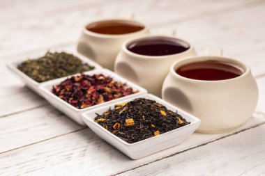 Beyaz ahşap zemin üzerinde kuru çay bardağı ve küçük kare tabaklar çay çeşitli tür