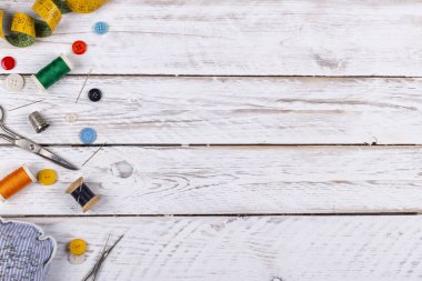 Beyaz ahşap masa metal makas, çeşitli düğmeleri ve renkli konu ve şerit metre yukarıdan dikiş biriktiricileri dağınık güzel set