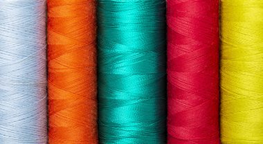 Dizilerin renkli canlı kırmızı, turuncu, sarı, lavanta ve turkuaz ipek dikiş makaralar üzerinde yakın çekim arka plan