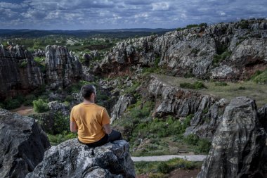 Yan görünümü tanınmayan adam uçurumun tepesinde oturan ve uzak Cerro del Hierro, Seville doğada dinlenirken arıyorsunuz