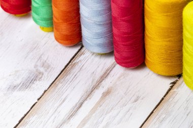 Beyaz ahşap masa üzerinde dikiş makaralar üzerinde renkli canlı ipek iş parçacığı yakın çekim arka plan