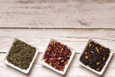 Kuru çay beyaz ahşap zemin üzerinde küçük kare tabaklar içinde farklı türde yukarıdan,