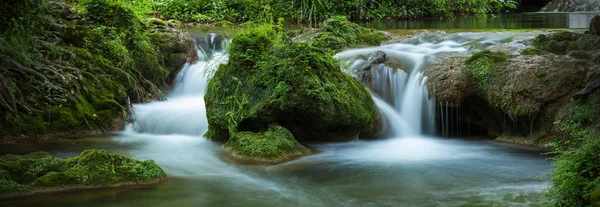 长时间暴露在绿色森林小池塘中的小瀑布全景 — 图库照片