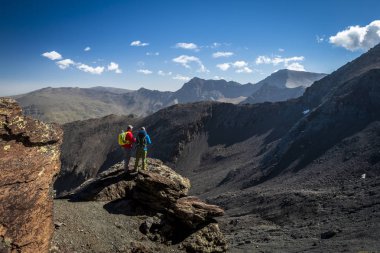 Kayanın üzerinde duran ve muhteşem Dağları güzel güneşli günde Sierra Nevada, Granada, İspanya arayan iki erkek yolcuları arkadan görünüm