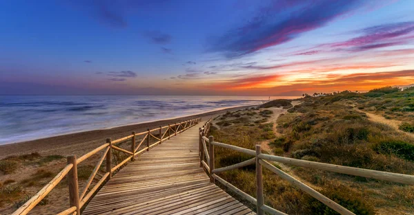 Coucher de soleil brillant ciel sur la mer et chemin de bois — Photo