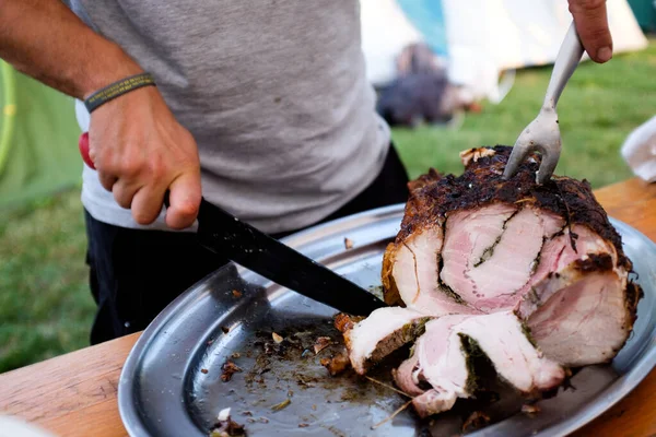 Lezzetli bir porchetta dilimleyen adam, geleneksel İtalyan sokak yemekleri.