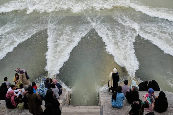 İsfahan, İran - Mayıs 12019: Khaju Köprüsü 'nde oturan insanlar köprünün altından akan olağandışı su olayına bakıyorlar