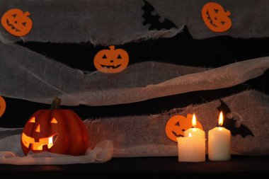 Balkabağı kafası siyah bir arka planda, gazlı bez ve dekorasyonlu.